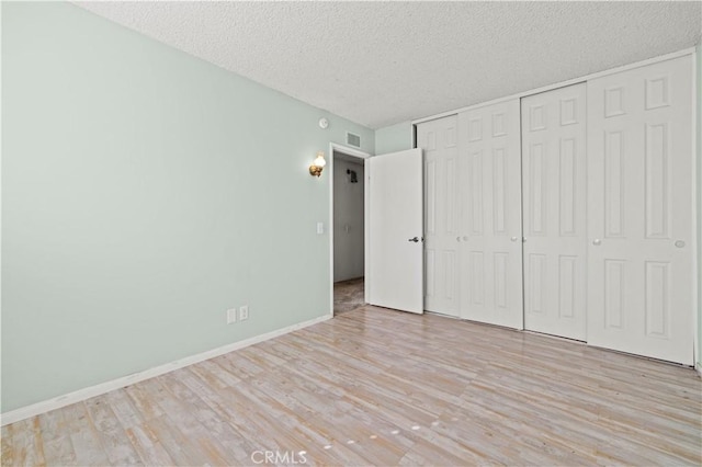 unfurnished bedroom with light hardwood / wood-style floors, a textured ceiling, and a closet