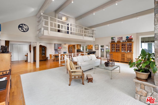 living room with beam ceiling, a high ceiling, and hardwood / wood-style flooring