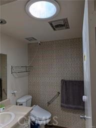 bathroom with toilet, vanity, and a shower with shower curtain