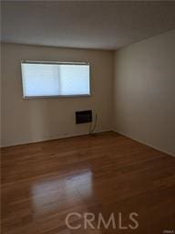 unfurnished room featuring hardwood / wood-style flooring and an AC wall unit