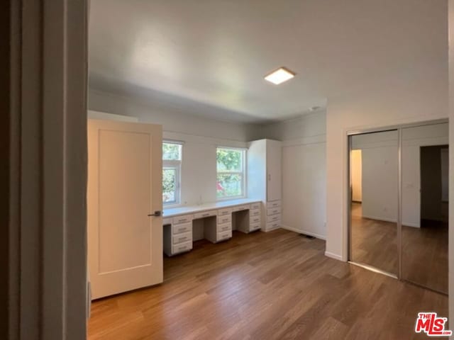 unfurnished bedroom featuring hardwood / wood-style flooring and built in desk