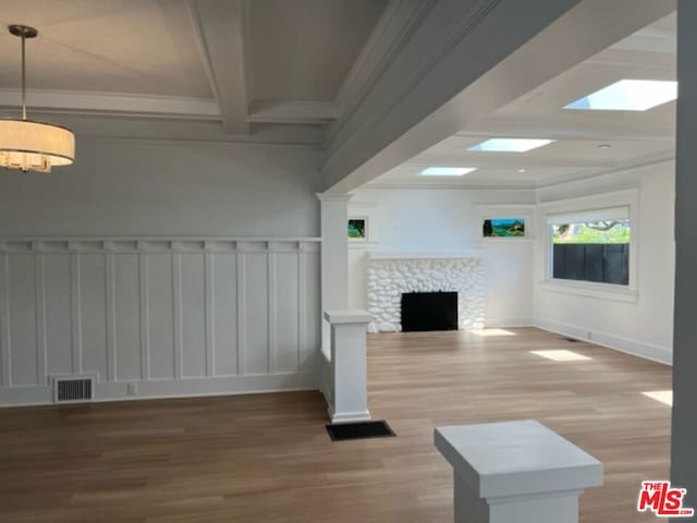 unfurnished living room with beam ceiling, hardwood / wood-style floors, a skylight, and a fireplace