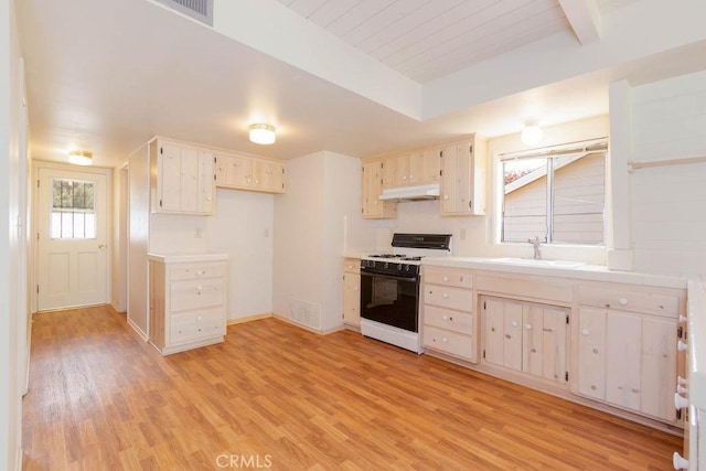 kitchen featuring sink, white gas range, beamed ceiling, and light hardwood / wood-style flooring