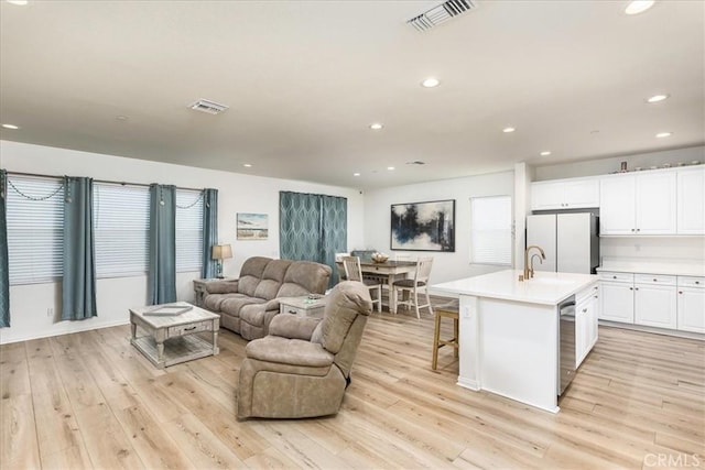 living area with light wood-type flooring, visible vents, and recessed lighting