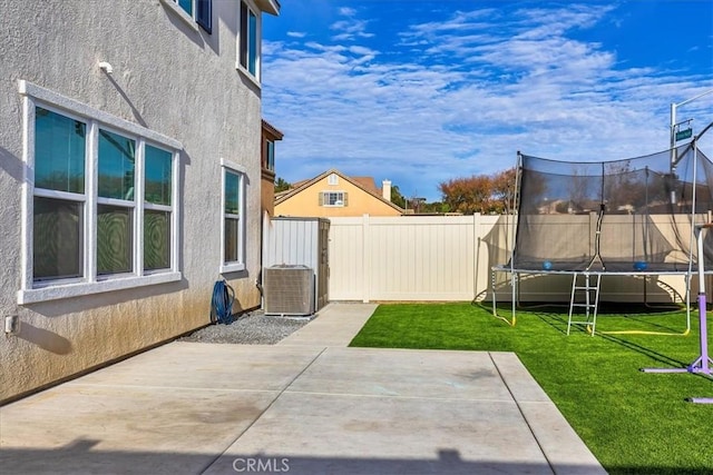 view of yard with a fenced backyard, central air condition unit, a patio, and a trampoline