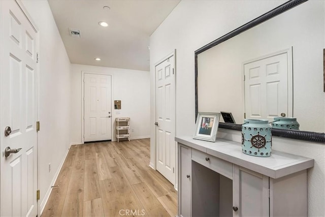 corridor with light wood finished floors, visible vents, recessed lighting, and baseboards