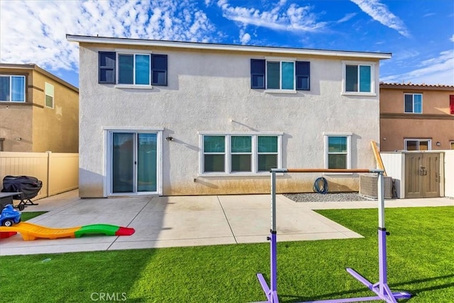 rear view of house with a patio area, stucco siding, a yard, and fence