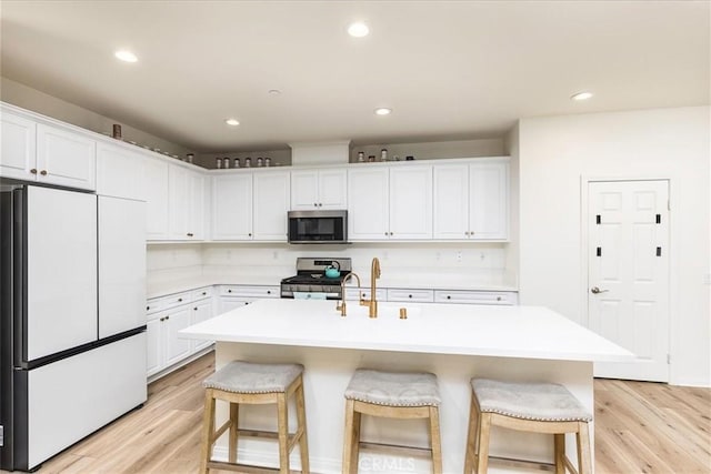 kitchen featuring stainless steel appliances, light wood-style floors, and a breakfast bar area