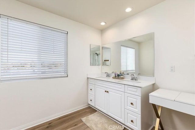 bathroom featuring double vanity, wood finished floors, baseboards, and a sink