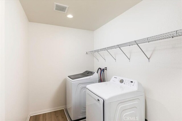 laundry area with hardwood / wood-style flooring and washing machine and dryer