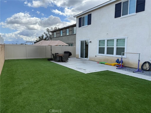 back of house with a yard, a patio area, stucco siding, and a fenced backyard