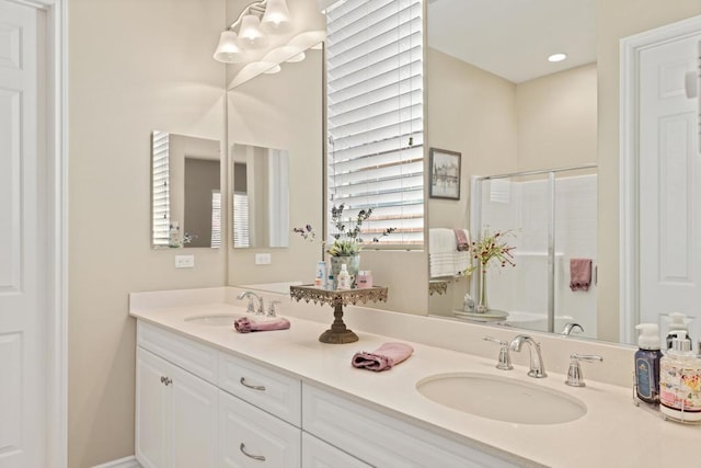 bathroom featuring a shower with shower door and vanity