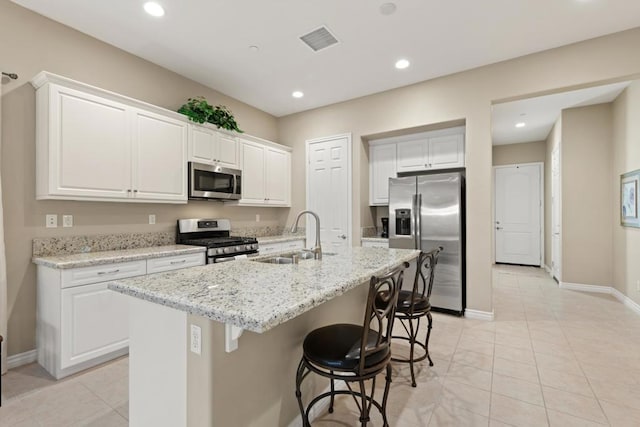 kitchen with a kitchen island with sink, sink, stainless steel appliances, and white cabinetry