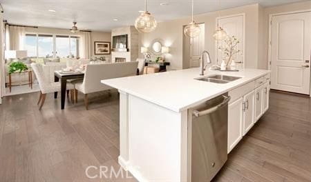 kitchen with a center island with sink, dishwasher, hanging light fixtures, white cabinets, and sink