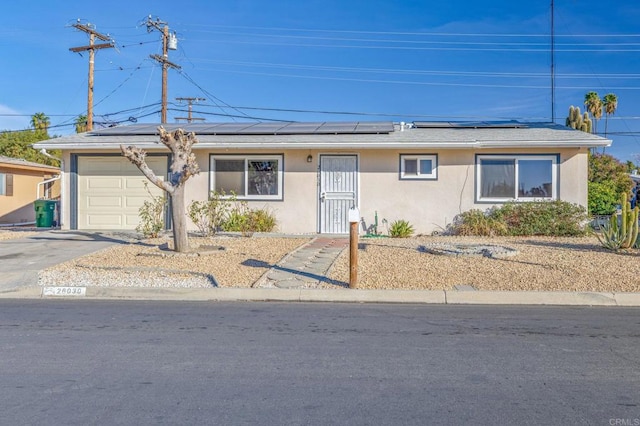 single story home featuring solar panels and a garage