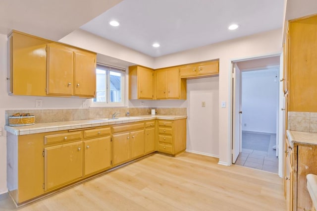 kitchen featuring sink, light hardwood / wood-style flooring, and tile counters