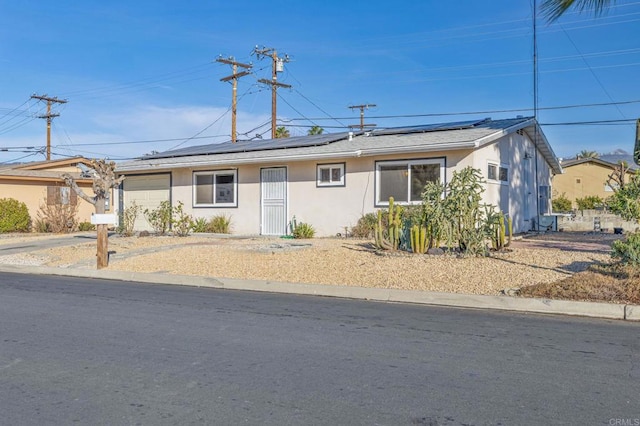 single story home featuring solar panels and a garage