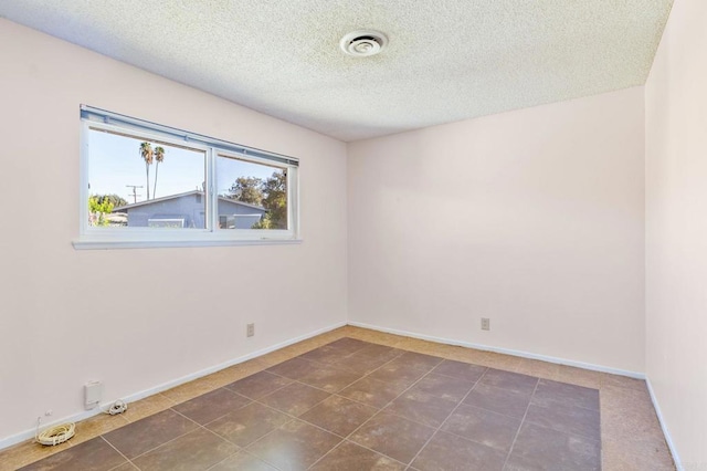 tiled spare room with a textured ceiling