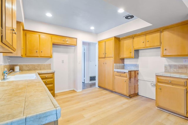 kitchen featuring tile counters, sink, and light hardwood / wood-style floors