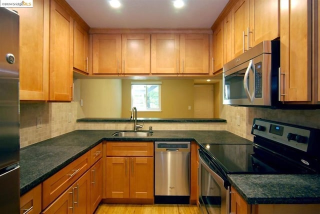 kitchen with sink, appliances with stainless steel finishes, and dark stone countertops