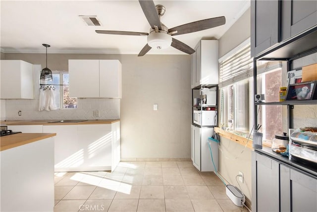 kitchen with hanging light fixtures, plenty of natural light, white cabinets, and ceiling fan