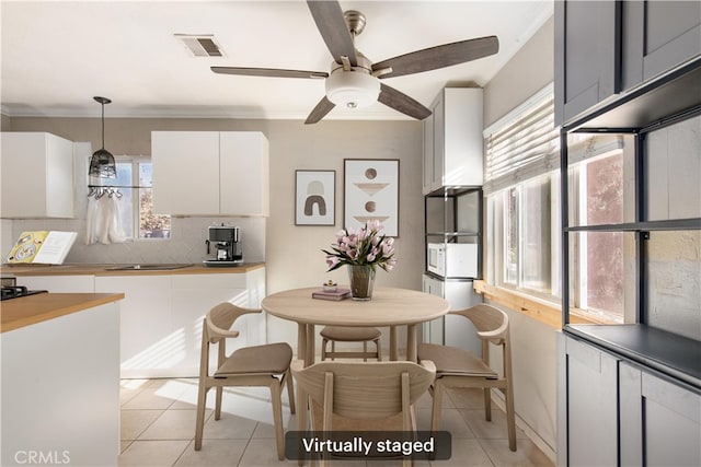 kitchen with plenty of natural light, pendant lighting, ceiling fan, decorative backsplash, and white cabinets