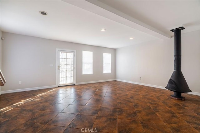 unfurnished living room featuring a wood stove and beamed ceiling