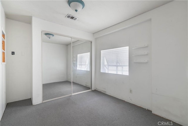 unfurnished bedroom featuring dark carpet and a closet