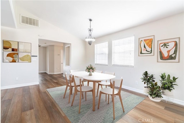 dining space featuring wood-type flooring and vaulted ceiling