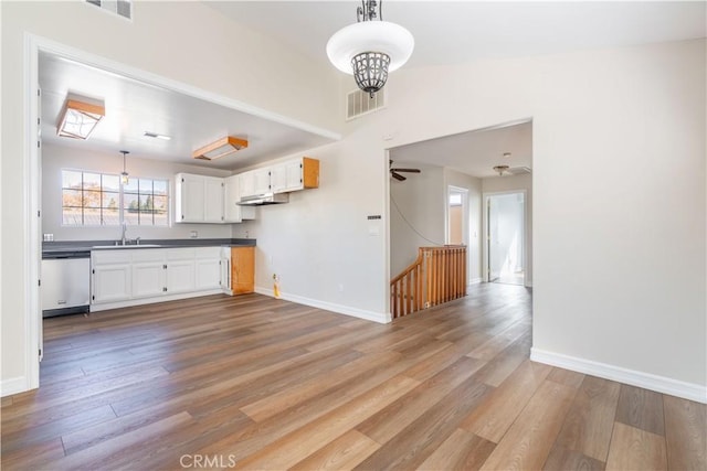 kitchen featuring stainless steel dishwasher, white cabinets, ceiling fan, and light hardwood / wood-style flooring