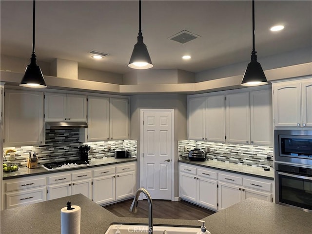 kitchen with backsplash, white cabinetry, stainless steel appliances, and hanging light fixtures