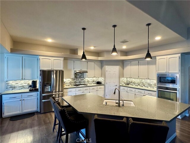 kitchen with stainless steel appliances, white cabinetry, a large island, and sink