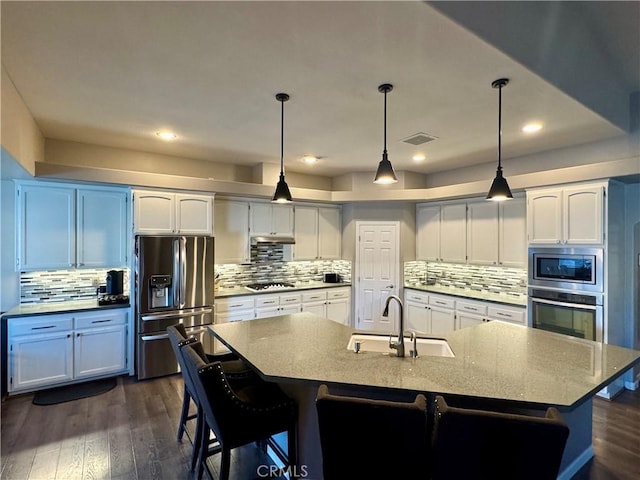 kitchen featuring sink, appliances with stainless steel finishes, white cabinetry, a spacious island, and decorative light fixtures