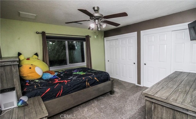 bedroom featuring a ceiling fan, carpet, visible vents, multiple closets, and a textured ceiling