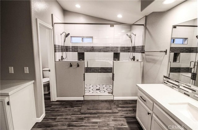 bathroom with vanity, wood finished floors, lofted ceiling, a stall shower, and toilet