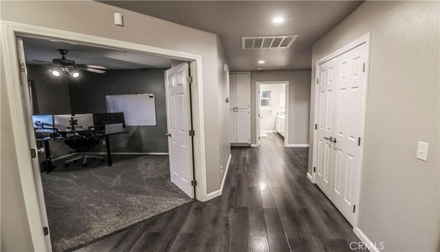 corridor with visible vents, baseboards, and dark wood-style flooring