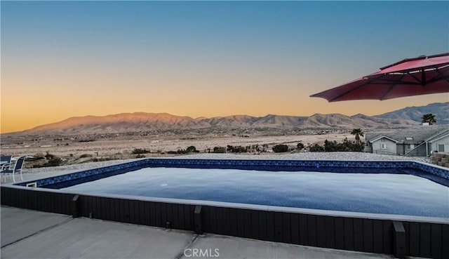 view of swimming pool with a mountain view and a hot tub