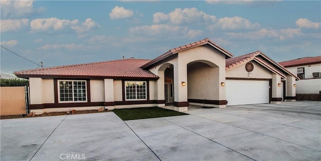 mediterranean / spanish-style home with a tiled roof, a garage, and stucco siding