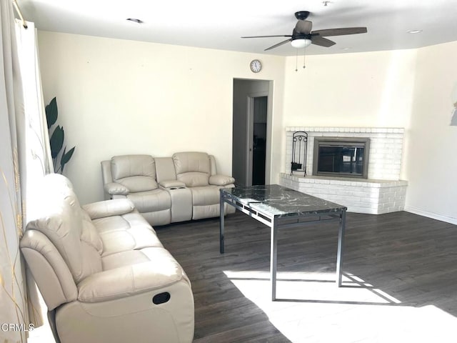 living room featuring dark wood-type flooring, a brick fireplace, and ceiling fan