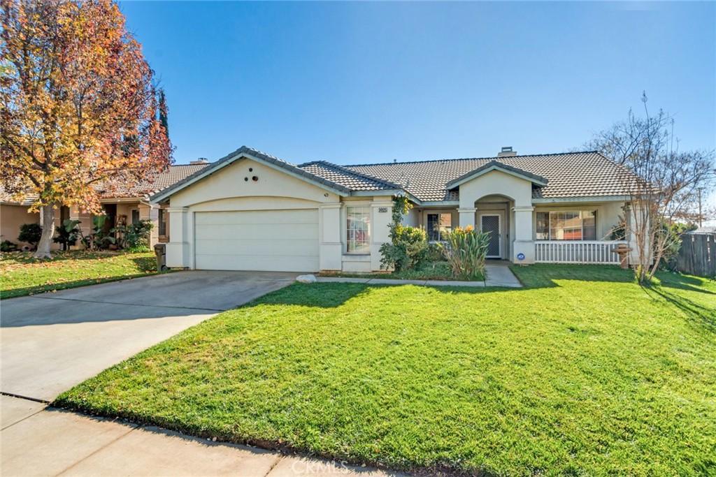 view of front of home featuring a tile roof, stucco siding, an attached garage, a front yard, and driveway