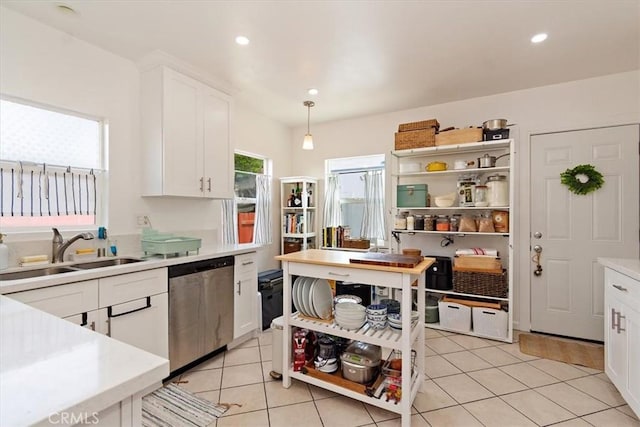 kitchen with dishwasher, pendant lighting, light tile patterned flooring, sink, and white cabinets