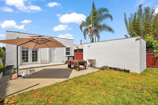 rear view of house featuring a lawn, french doors, and a patio area