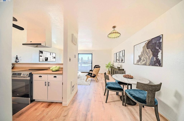 kitchen with light hardwood / wood-style flooring, white cabinets, hanging light fixtures, and stainless steel range with electric stovetop