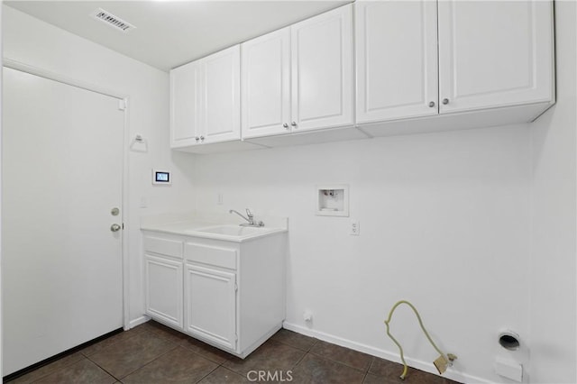 clothes washing area featuring gas dryer hookup, sink, dark tile patterned floors, cabinets, and washer hookup