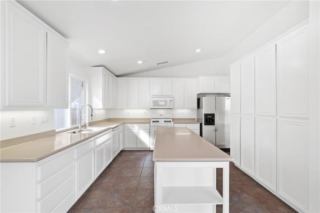 kitchen featuring lofted ceiling, sink, white appliances, white cabinets, and a kitchen island