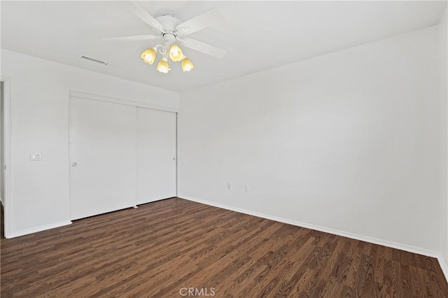 unfurnished bedroom with dark hardwood / wood-style floors, a closet, and ceiling fan