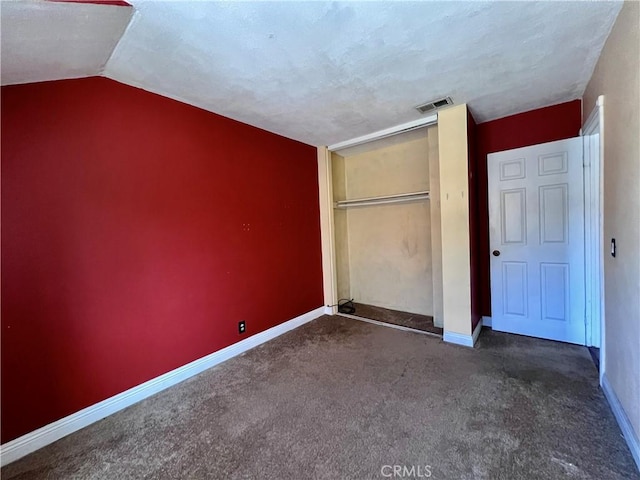 unfurnished bedroom with lofted ceiling, a closet, and dark carpet