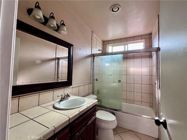 full bathroom featuring toilet, combined bath / shower with glass door, tasteful backsplash, tile patterned flooring, and vanity