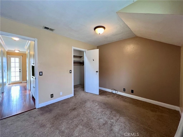 unfurnished bedroom with carpet flooring, a closet, crown molding, and vaulted ceiling