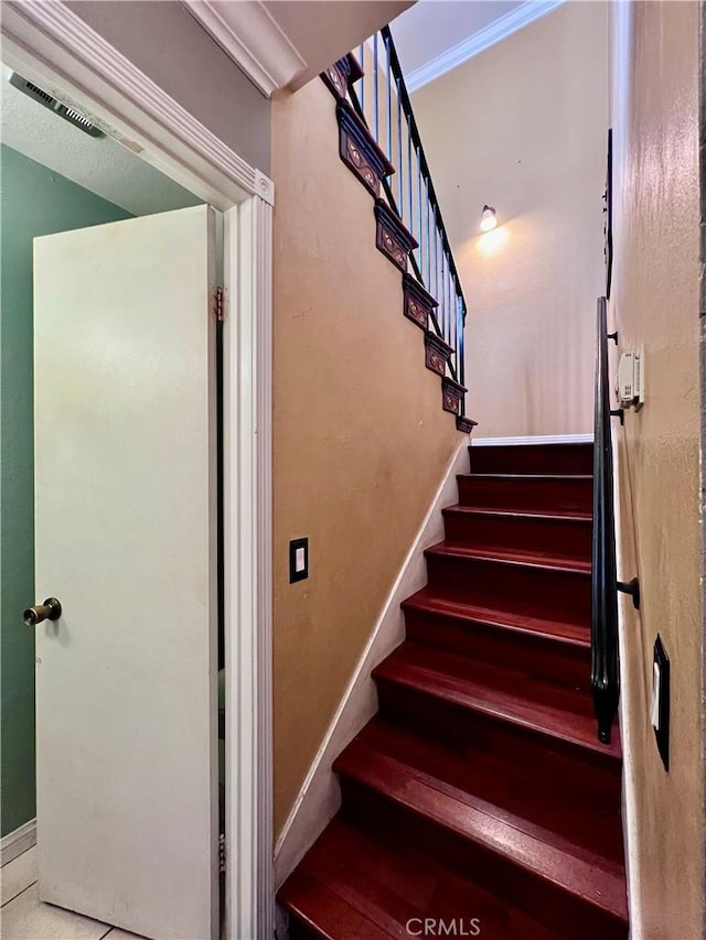 stairway with tile patterned flooring and crown molding